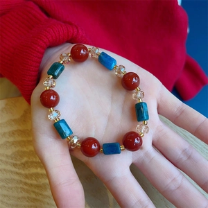 Detail of red agate and blue-grey beads bracelet worn on hand over red sweater