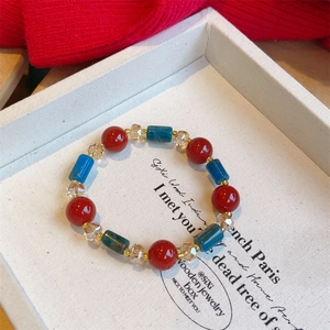 Macro detail of vintage red agate and blue bead bracelet with crystal accents on a tray