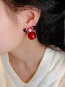 Macro view of red bow earrings with pearls on model, showing vintage heavy craft style