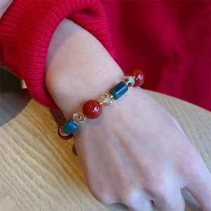 Vintage red agate and green crystal beaded bracelet with gold spacers on woman's wrist