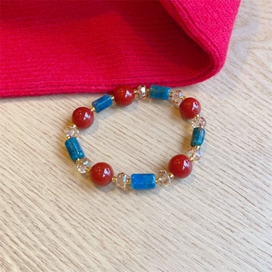 Handmade red agate and blue crystal beaded bracelet with gold spacers on wood