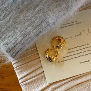 Elegant gold drop hoop earrings with geometric faceted texture on a vintage card