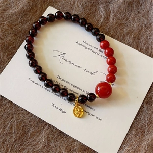 Detailed macro view of garnet beaded bracelet with gold pendant on vintage card background