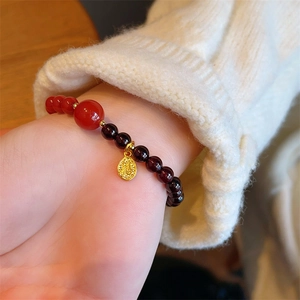 Vintage garnet bead bracelet featuring red agate accent and gold carved coin charm