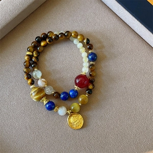 Detail of beaded bracelets with tiger eye stones, blue crystal, and a gold Buddha charm