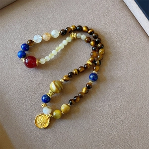 Double-wrap bead bracelet with tiger eye stones and a gold lion coin charm