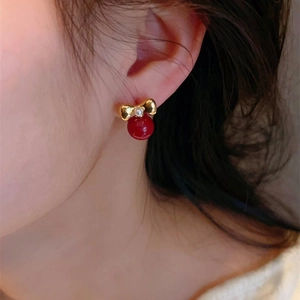 Festive red pearl bow earrings in gold finish worn on ear for a sweet vintage look