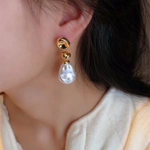 Baroque pearl earrings featuring irregular shapes and gold accents on a female model