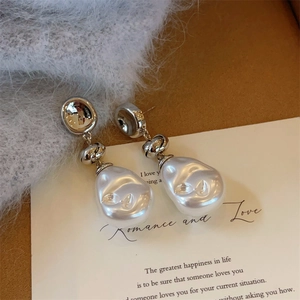 Close-up of elegant silver twisted earrings with large white baroque pearls on art card