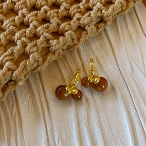 Tiger eye bead earrings in gold finish set against a textured minimalist background