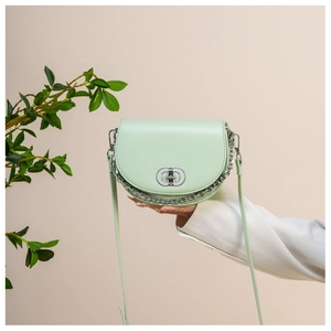 Detail of mint green saddle bag featuring silver double-ring buckle and decorative chain