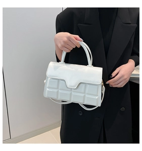 Detail der weißen Handtasche aus glänzendem Leder mit geprägtem Gittermuster