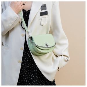 Detailed shot of mint green crescent bag with silver chain and metal lock on a model outfit