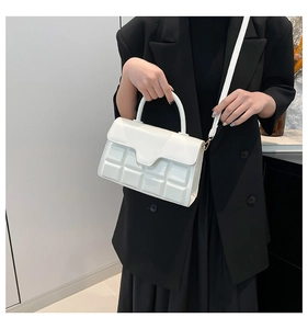 Detailansicht der weißen Tasche mit Waffelstruktur und gewellter Klappe am Griff