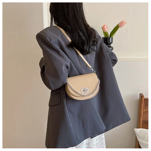 Beige semi-circular crossbody saddle bag with silver chain strap shown on a model