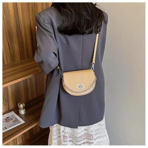 Model view of beige saddle bag with silver chain strap and circular metal buckle detail