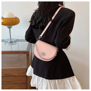 Pink semi-circle saddle bag with silver chain strap shown worn across the body
