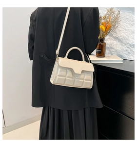 Detail der cremeweißen Handtasche mit 3D-Schokoladenstruktur auf schwarzem Blazer