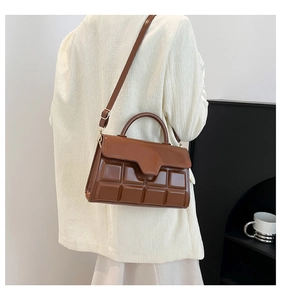 Braune Handtasche mit Schokoladenmuster und Glanzoptik in einer Lifestyle-Umgebung