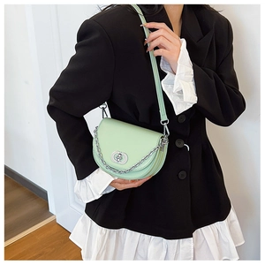 Detail of mint green saddle bag with silver ring buckle and chain on black blazer