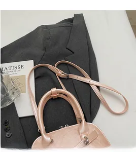 Detail view of pink leather shell bag with smooth adjustable long shoulder strap and handle