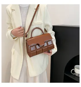Detail einer schokobraunen Handtasche aus Glanzleder mit quadratischer 3D-Reliefprägung