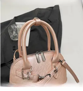 Close-up of pink shell handbag with durable round handle and metal chain on a grey blazer