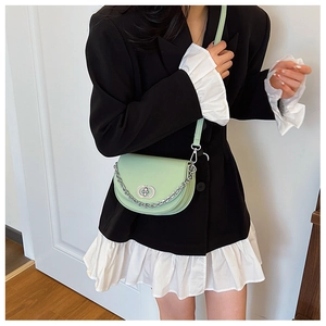 Detail of mint green half-moon crossbody bag with silver chain and metal turn-lock buckle