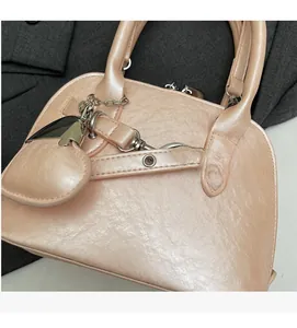 Close-up of pink shell bag with glossy wrinkled texture and heart pendant