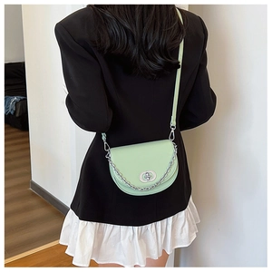 Detail view of mint green crescent crossbody bag with silver chain on model