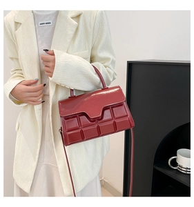 Detail der dunkelroten Lackleder-Handtasche mit einer 3D-geprägten quadratischen Textur