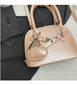 Detail of pink shell bag with pearlescent finish and large heart-shaped charm accessory
