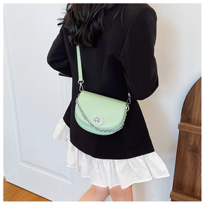 Detail of mint green half-moon crossbody bag with silver chain on model in black suit