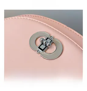 Detailed macro view of the silver CD logo metal clasp on a soft pink leather bag