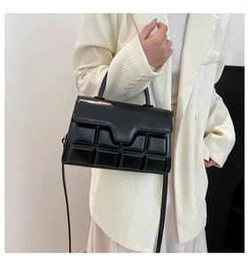 Detail der schwarzen rechteckigen Handtasche mit glänzender 3D-Steppquadrat-Textur