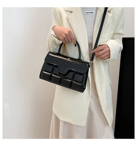 Detail einer schwarzen glänzenden Handtasche mit modernem geometrischem 3D-Prägemuster