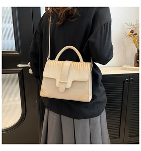 Detail of cream crocodile embossed texture and gold buckle on stylish handbag