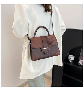 Side view of brown faux crocodile leather handbag styled with a white blazer