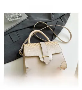 Detail view of beige crossbody bag with faux crocodile pattern and gold hardware accents