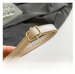 Detail view of the beige crocodile-pattern leather strap with gold adjustable metal buckle
