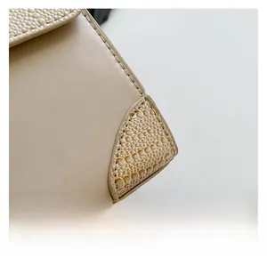 Detailed close-up of cream leather stitching and crocodile pattern on a crossbody bag