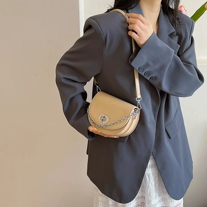 Beige semi-circular crossbody bag with silver chain and metal clasp shown on model