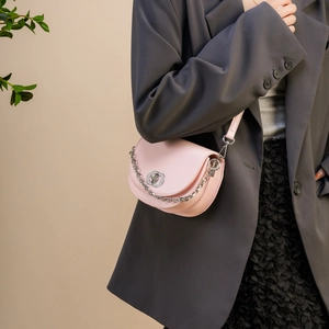 Pink semi-circle saddle bag with silver chain worn by a model in a grey blazer