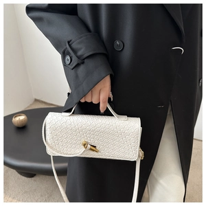 Détail d'un sac en cuir tressé blanc avec fermoir noeud doré sur fond de manteau noir