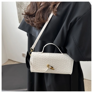 Détail de la texture tressée d'un sac baguette blanc avec fermoir tournant doré