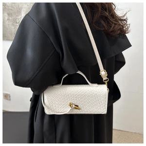Détail de la texture crocodile blanc sur un sac rectangulaire avec fermoir doré