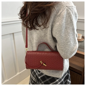 Détail du sac à main rouge en cuir tressé avec fermoir rotatif et poignée élégante