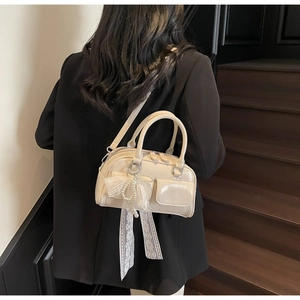 Detail of cream Boston bag with lace bow, pearl charm and adjustable shoulder strap