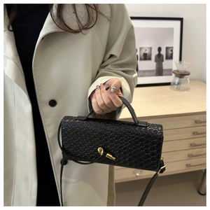 Détail du sac à main en cuir tressé noir avec fermoir boule doré et bandoulière