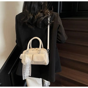 Detail of off-white Boston bag with front pockets and lace bow decoration worn crossbody